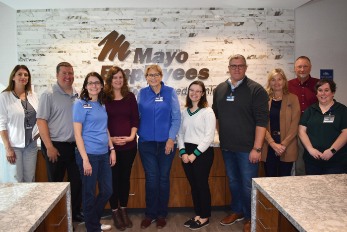 A group of ten people stand in front of MEFCU sign