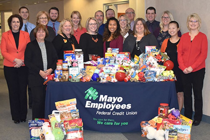 eighteen mefcu employees stand around table covered in donations
