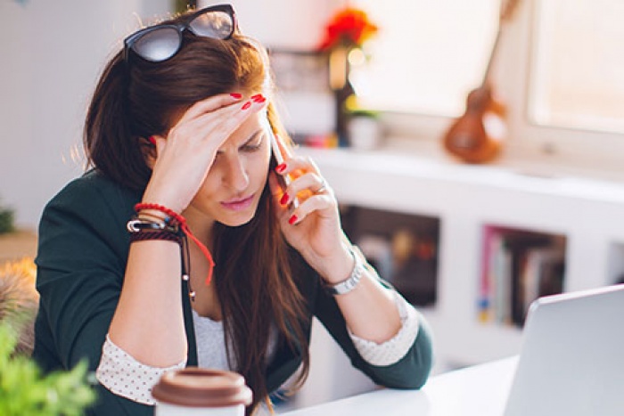 woman talking on cell phone with her hand on her forehead appearing frustrated