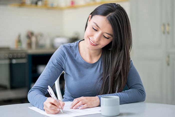 woman writing at table with cup of coffee