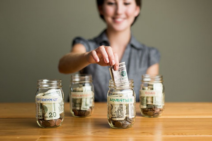 woman putting cash savings into jars to budget