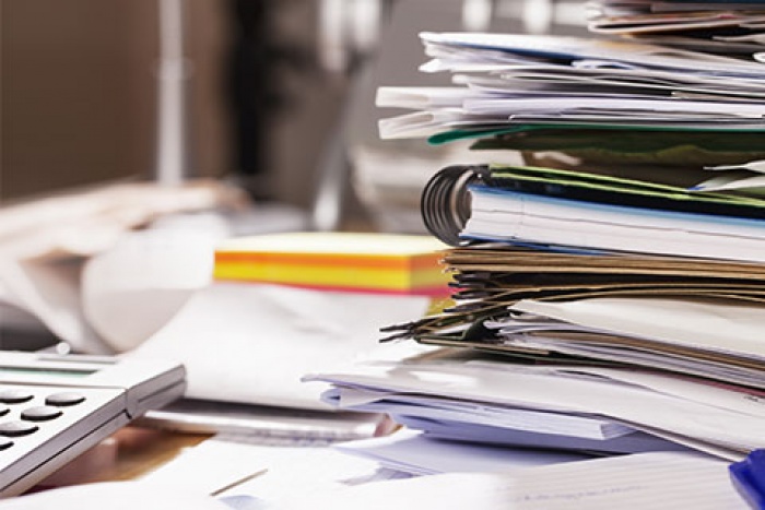 calculator and notebooks stacked on cluttered desk