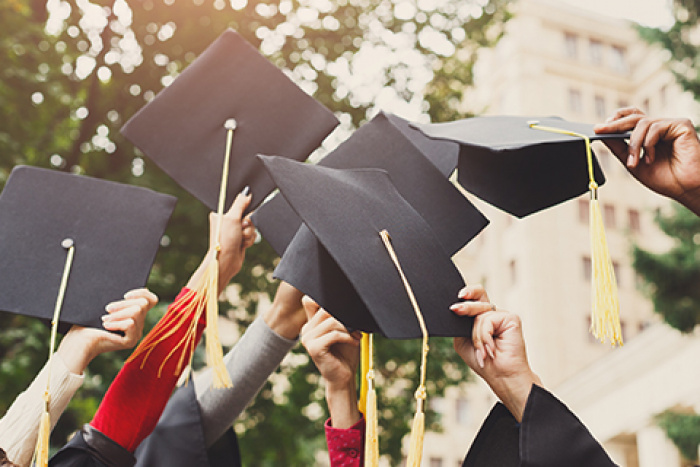 graduates holding up their caps