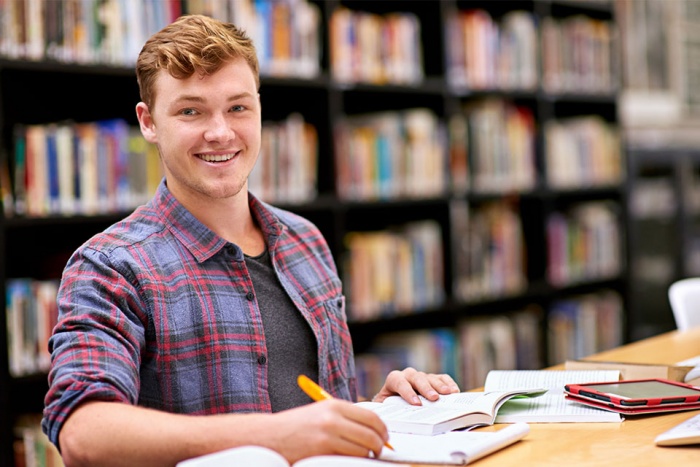 young man in library smiling at camera