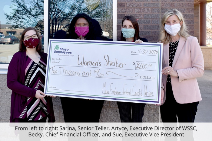 four women holding oversize check to donate to women's shelter